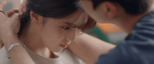 A Man Is Putting A Ring On A Woman 'S Ear . GIF