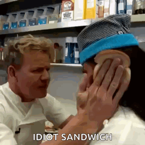 A Man Is Putting A Sandwich On Another Man 'S Ear In A Kitchen . GIF