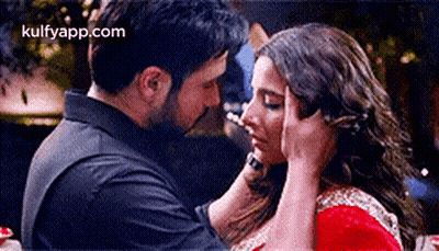 A Man Is Putting His Hand On A Woman 'S Forehead While They Are Kissing . GIF