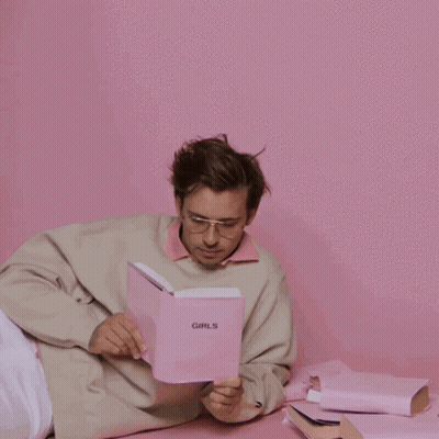 A Man Is Reading A Book Called Girls GIF