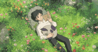 a man is reading a book while laying in the grass