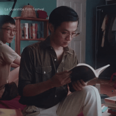 A Man Is Reading A Book With La Guarimba Film Festival Written On The Bottom GIF