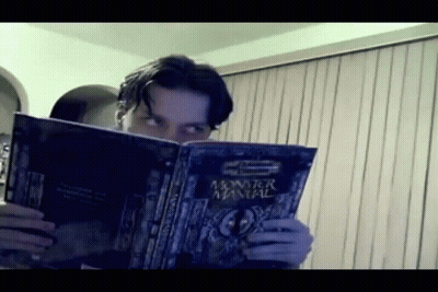 A Man Is Reading A Monster Manual GIF