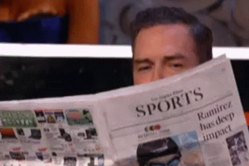 A Man Is Reading A Sports Newspaper With His Eyes Closed GIF