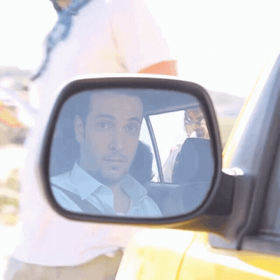 A Man Is Reflected In The Side Mirror Of A Yellow Car GIF