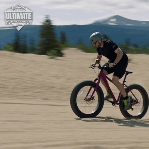 A Man Is Riding A Bicycle On A Dirt Road With The Words Canada 'S Ultimate Challenge In The Background GIF