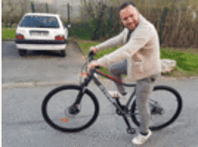A Man Is Riding A Bicycle On A Street Next To A Car . GIF