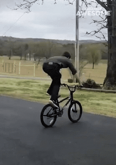 A Man Is Riding A Bike Down A Road And The Words Awesome Are On The Bottom Right GIF