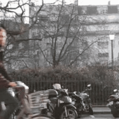 A Man Is Riding A Bike Down A Street In Front Of A Row Of Parked Motorcycles . GIF