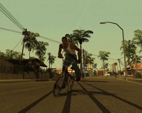 A Man Is Riding A Bike Down A Street With Palm Trees GIF