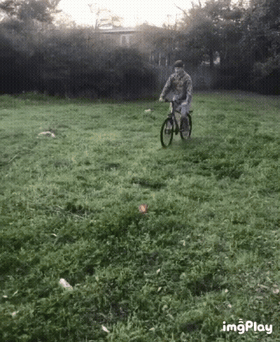 A Man Is Riding A Bike In A Grassy Field With The Hashtag Imgplay In The Lower Right Corner GIF