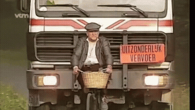 A Man Is Riding A Bike In Front Of A Truck With A Sign On It That Says Uitzonderlijk Vervoer GIF