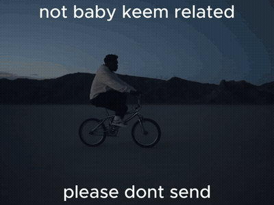 A Man Is Riding A Bike In The Dark With The Words Not Baby Keem Related Below Him GIF