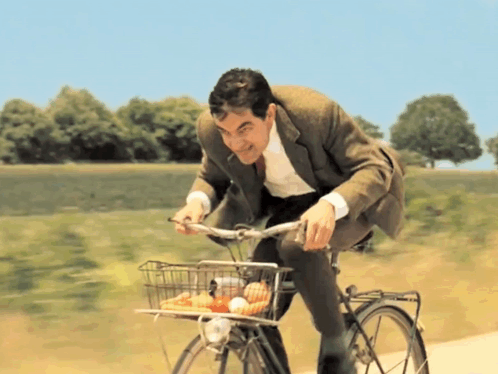 A Man Is Riding A Bike With A Basket Full Of Food GIF