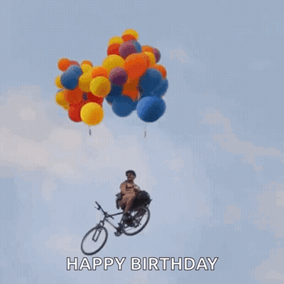 A Man Is Riding A Bike With Balloons Hanging From It In The Air . GIF