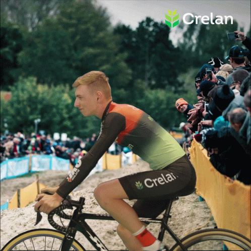 A Man Is Riding A Bike With Crelan On His Shorts GIF