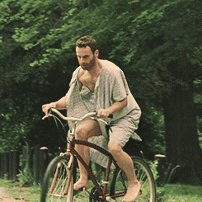 A Man Is Riding A Bike Without A Shirt On In A Park GIF