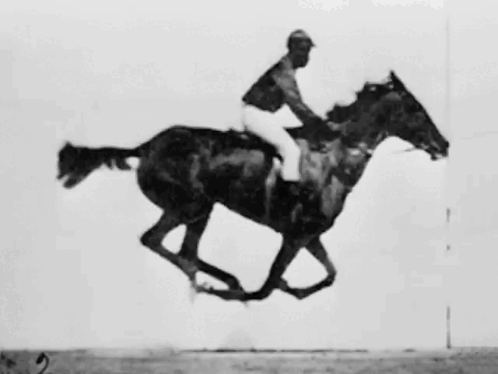 A Man Is Riding A Black Horse In A Black And White Photo GIF