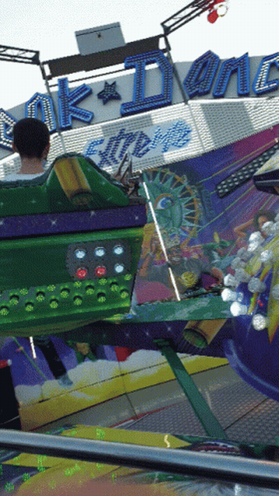 A Man Is Riding A Carnival Ride That Says ' Ak Dynamite Extreme ' On It GIF
