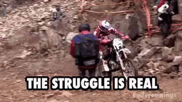 A Man Is Riding A Dirt Bike On A Rocky Trail While Another Man Sits On The Back Of It . GIF