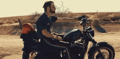 A Man Is Riding A Harley Davidson Motorcycle Down A Dirt Road GIF