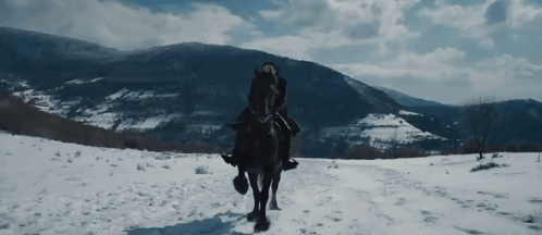 A Man Is Riding A Horse In The Snow GIF