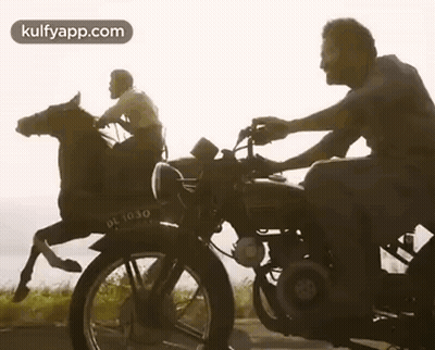 A Man Is Riding A Horse On A Motorcycle . GIF