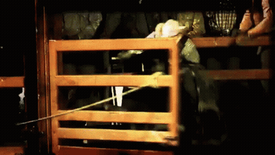 A Man Is Riding A Horse Through A Wooden Fence At A Rodeo GIF