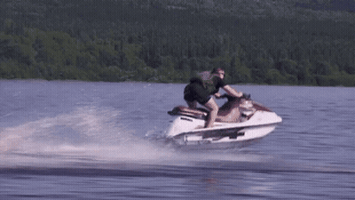 A Man Is Riding A Jet Ski In A Lake GIF