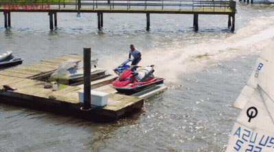 A Man Is Riding A Jet Ski In The Water Near A Dock GIF