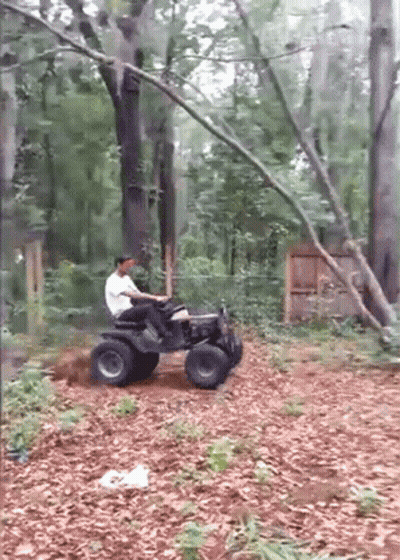 A Man Is Riding A Lawn Mower Through A Forest GIF