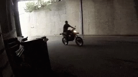 A Man Is Riding A Motorcycle Down A Street In A Tunnel . GIF