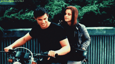 A Man Is Riding A Motorcycle Next To A Woman Who Is Standing Behind Him And The Words Skyfallmodellife Tumblr Are Visibl GIF