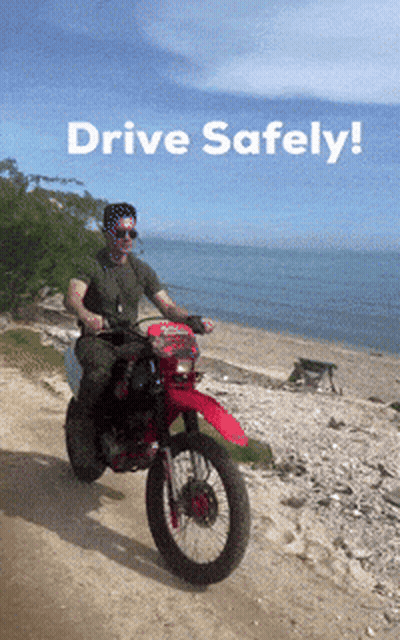 A Man Is Riding A Motorcycle On A Dirt Road With The Words Drive Safely Written Above Him GIF