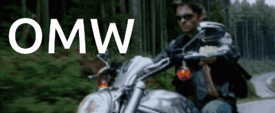 A Man Is Riding A Motorcycle On A Road With The Word Omw Written Above Him GIF