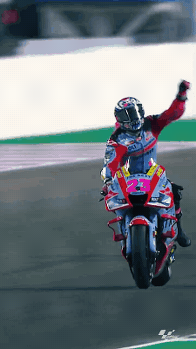 A Man Is Riding A Motorcycle On A Track With His Arm Up GIF