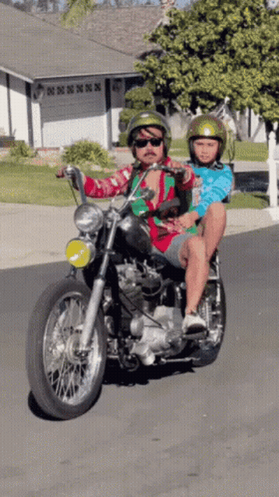 A Man Is Riding A Motorcycle With A Child On His Back GIF