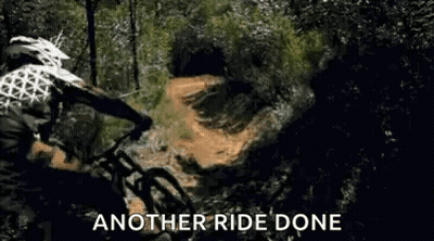 A Man Is Riding A Mountain Bike Down A Dirt Road . GIF