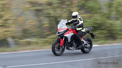 A Man Is Riding A Red And White Motorcycle On A Road GIF