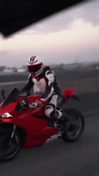 A Man Is Riding A Red Motorcycle With A Helmet That Has The Letter G On It GIF