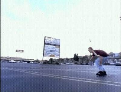 A Man Is Riding A Roller Skate In A Parking Lot While Holding A Sign . GIF