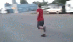 A Man Is Riding A Skateboard Down A Street In Front Of A Building . GIF