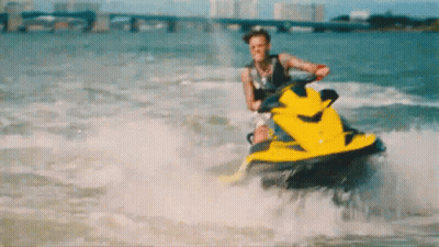 A Man Is Riding A Yellow Jet Ski On The Water GIF