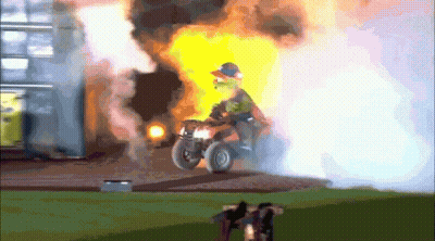 A Man Is Riding An Atv In Front Of A Building That Is On Fire GIF