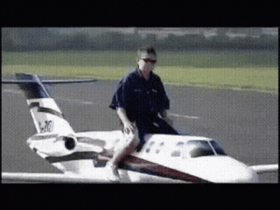 A Man Is Riding On The Back Of A Small Airplane With The Numbers N70 On The Tail GIF