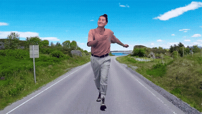 A Man Is Running Down A Road With A Sign That Says No Trucks GIF