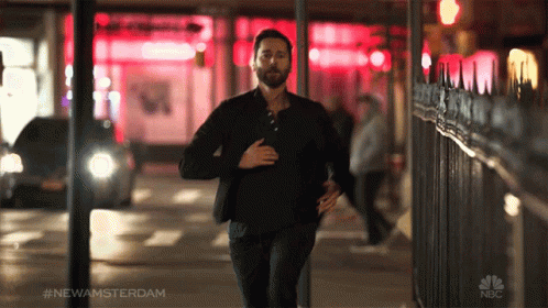A Man Is Running Down A Street With The Hashtag #Newamsterdam On The Bottom GIF