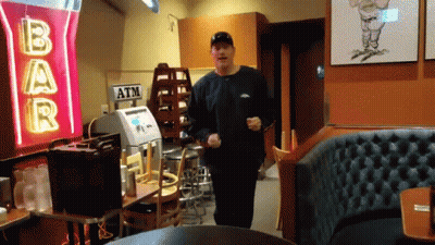 A Man Is Running In Front Of A Bar Sign GIF