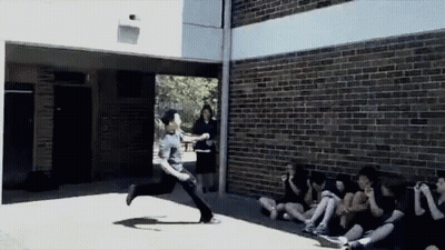 A Man Is Running In Front Of A Group Of People GIF