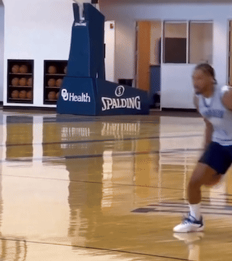 A Man Is Running On A Basketball Court With A Spalding Sign Behind Him GIF